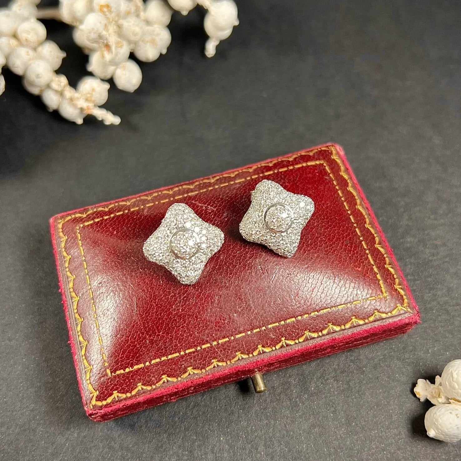 A pair of diamond cluster stud earrings in white gold, on an antique box
