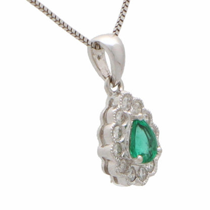 Emerald and diamond cluster pendant in white gold.