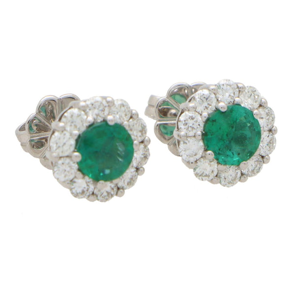 Emerald and diamond cluster earrings set in white gold.