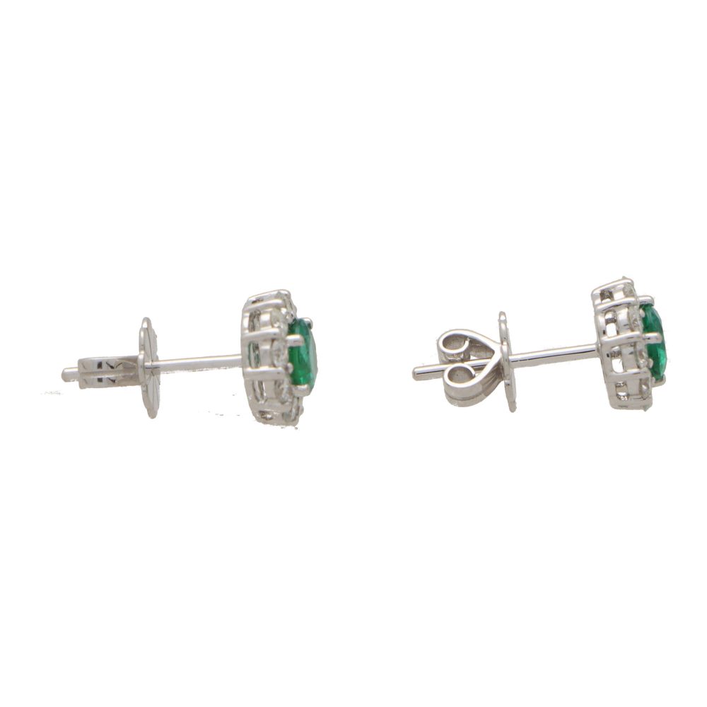 Emerald and diamond cluster earrings set in white gold.