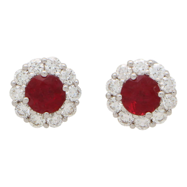 A pair of round ruby and diamond cluster earrings on a white background