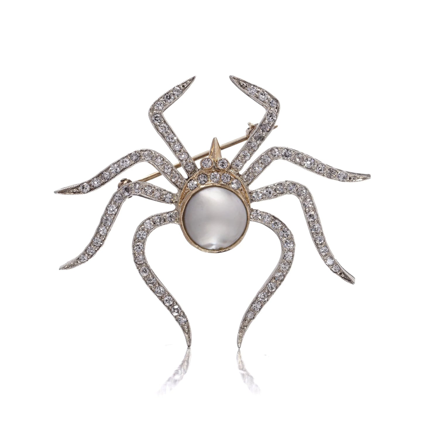 A spider brooch set with a pearl and diamonds, in gold and silver, on a white background