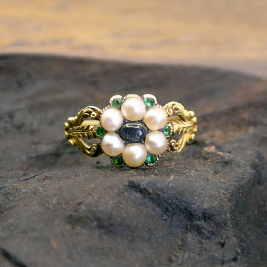 A decorative cluster ring with a cabochon moonstone, pearls and emeralds, with ornate shoulders in yellow gold