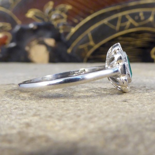 A beautiful contemporary ring featuring a 0.50ct emerald cut emerald with a diamond surround. With princess and modern brilliant cut diamonds alternating around the emerald, this ring has a total of 0.35ct diamonds allowing it to sparkle beautifully on the finger all set in platinum in a millegrain edge.