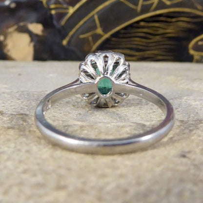 A beautiful contemporary ring featuring a 0.50ct emerald cut emerald with a diamond surround. With princess and modern brilliant cut diamonds alternating around the emerald, this ring has a total of 0.35ct diamonds allowing it to sparkle beautifully on the finger all set in platinum in a millegrain edge.