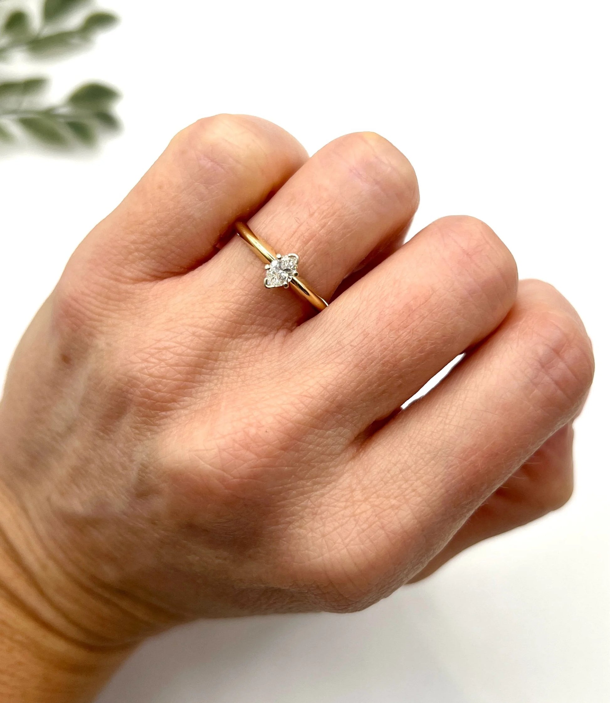 A marquise diamond solitaire ring in yellow and white gold, modelled on a hand