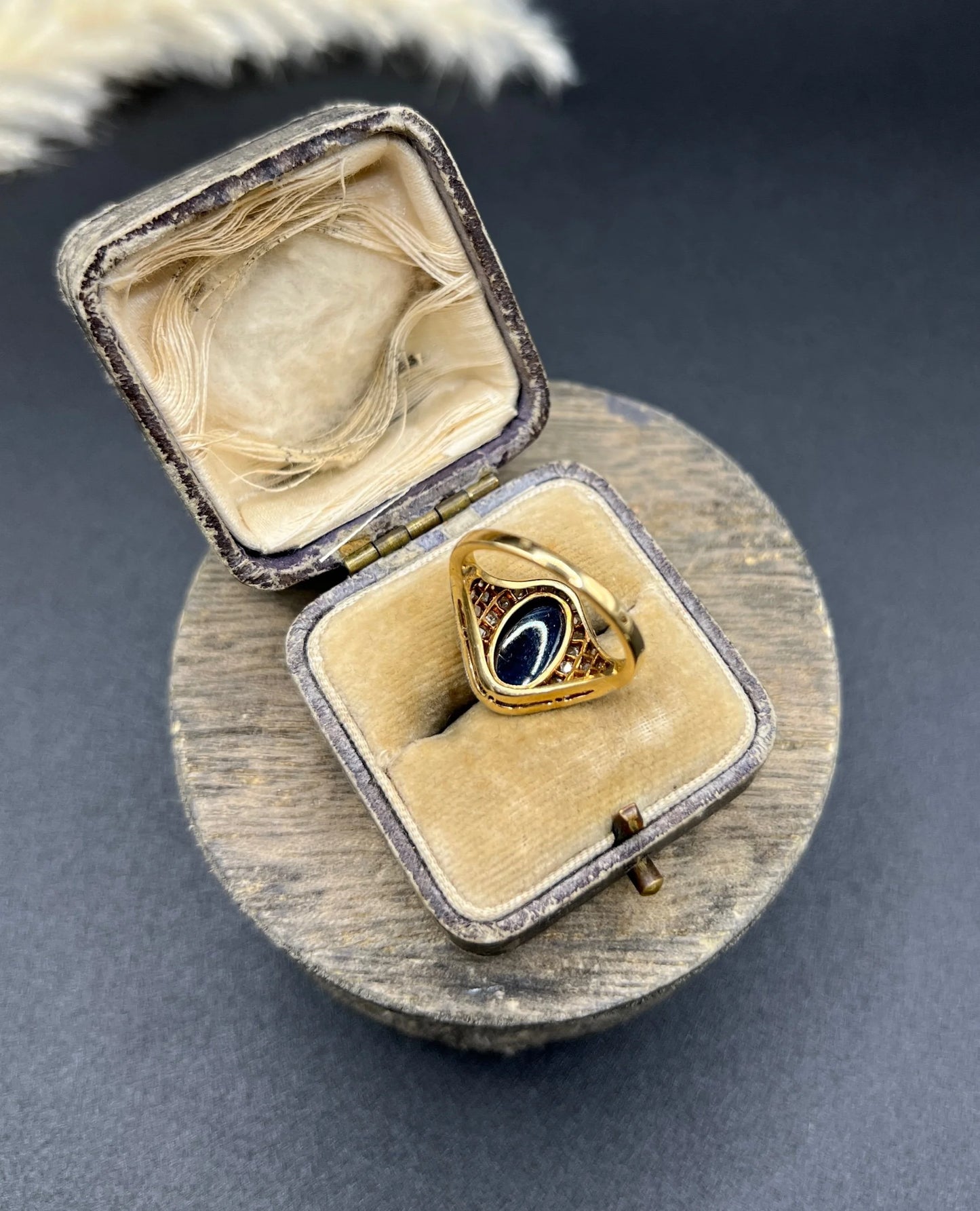 An oval cabochon sapphire and diamond fancy cluster ring in yellow and white gold, in a ring box