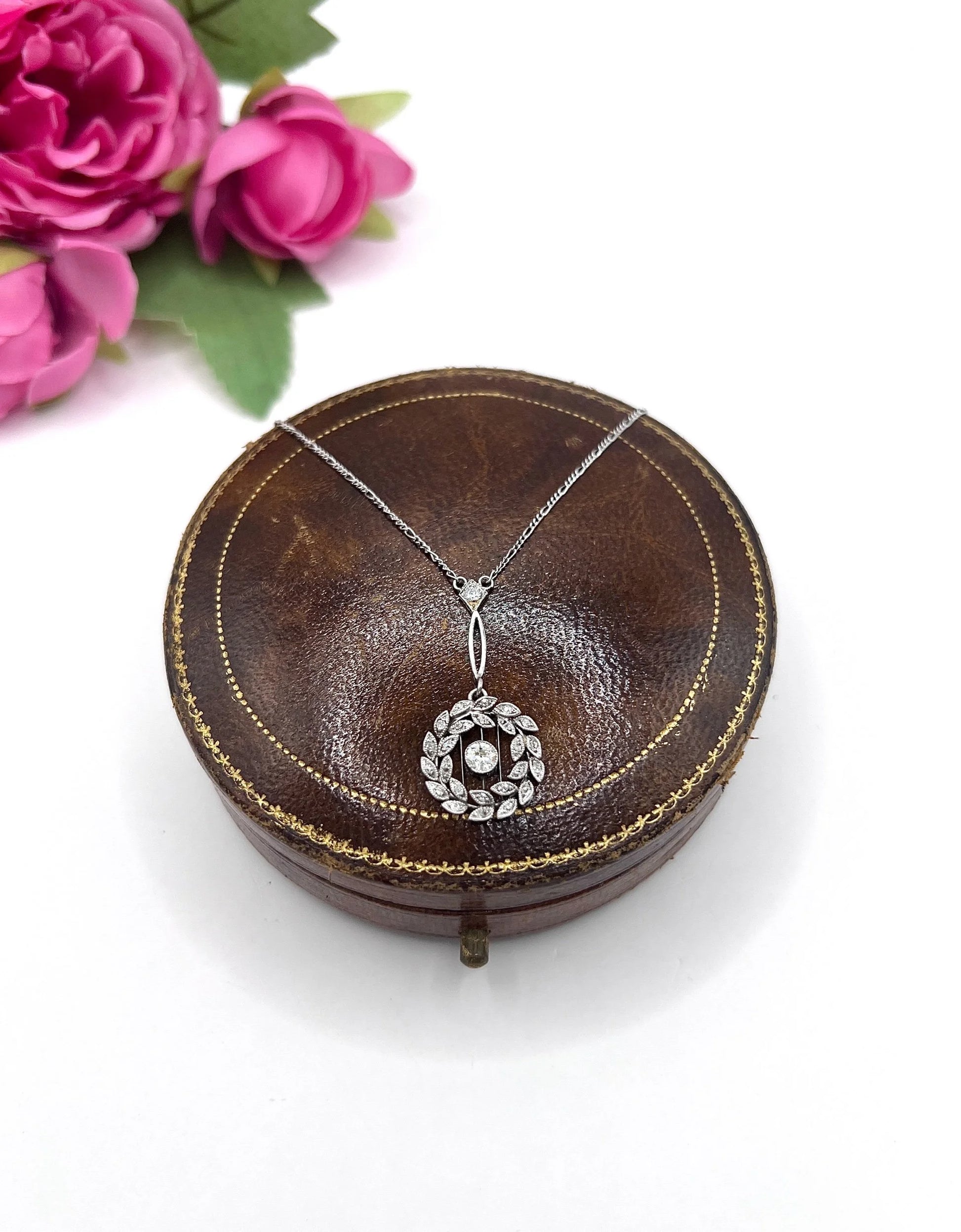 A platinum floral wreath pendant with diamonds on a platinum chain