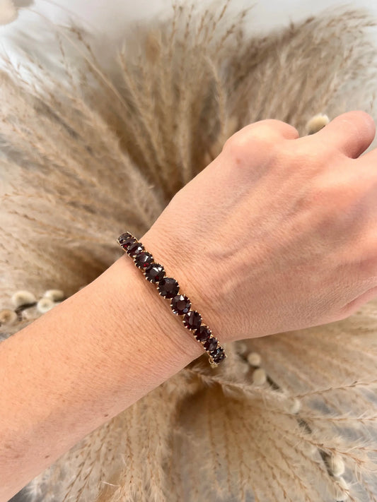 A yellow gold garnet bangle bracelet, modelled on a wrist