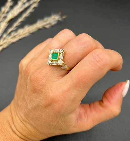 A gold and platinum ring with a centre emerald and diamond surround, modelled on a hand