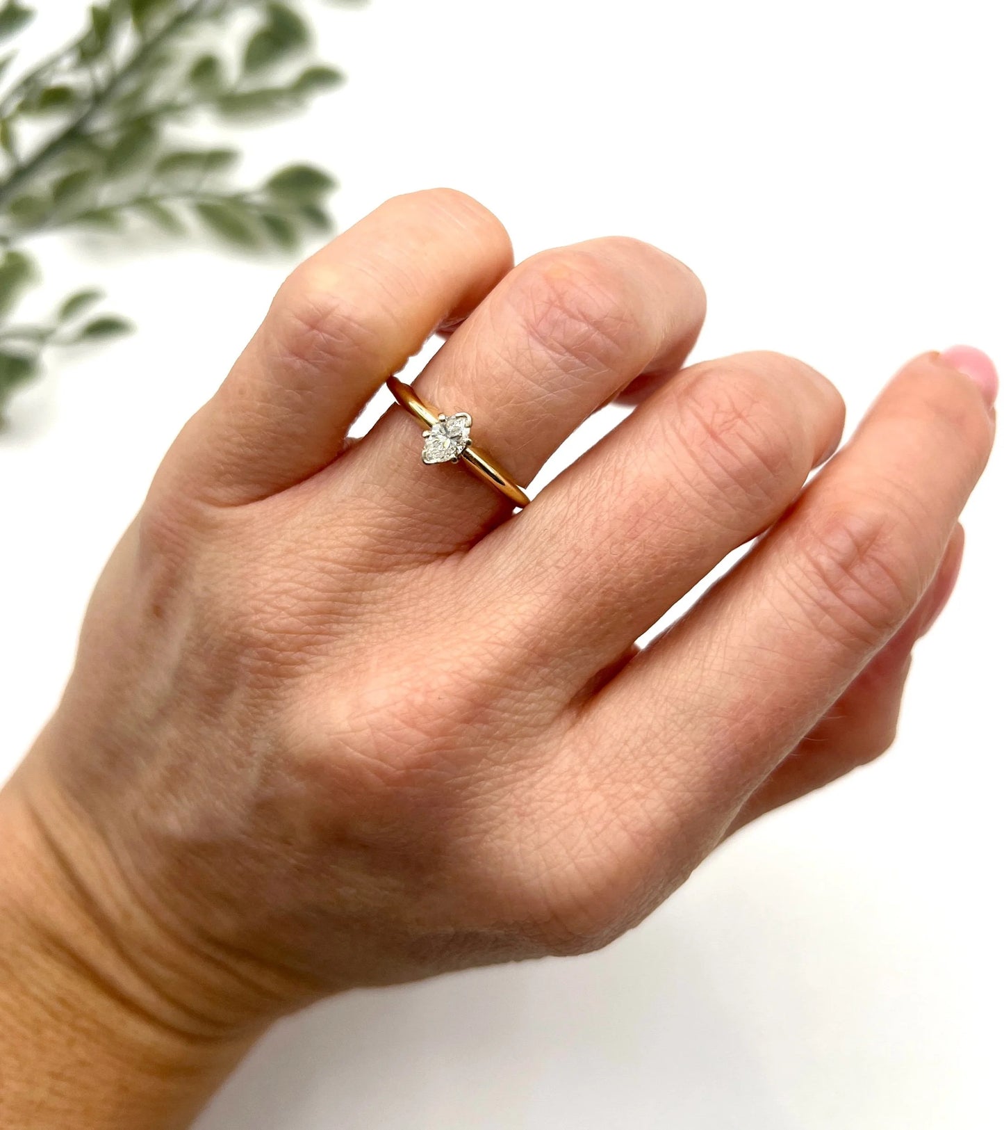 A marquise diamond solitaire ring in yellow and white gold, modelled on a hand