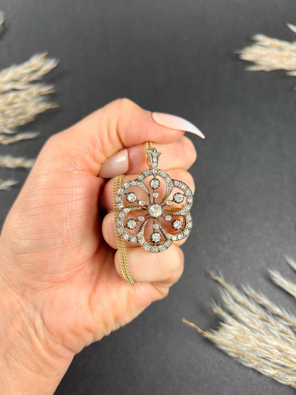 A floral design diamond set pendant/brooch, held in a hand