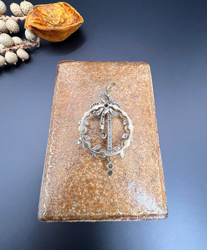 A pearl and diamond bow pendant in gold and platinum