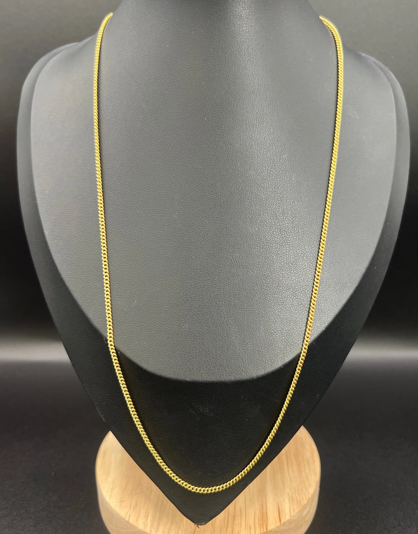 A yellow gold chain necklace, on a black jewellery bust