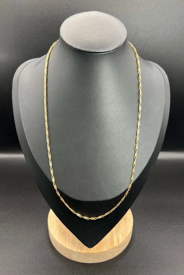 A gold paperclip link chain necklace, on a black bust