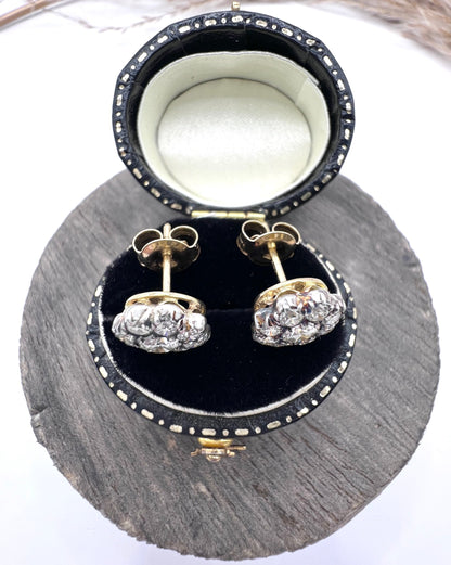 A pair of diamond daisy cluster stud earrings in yellow and white gold, in an earring box