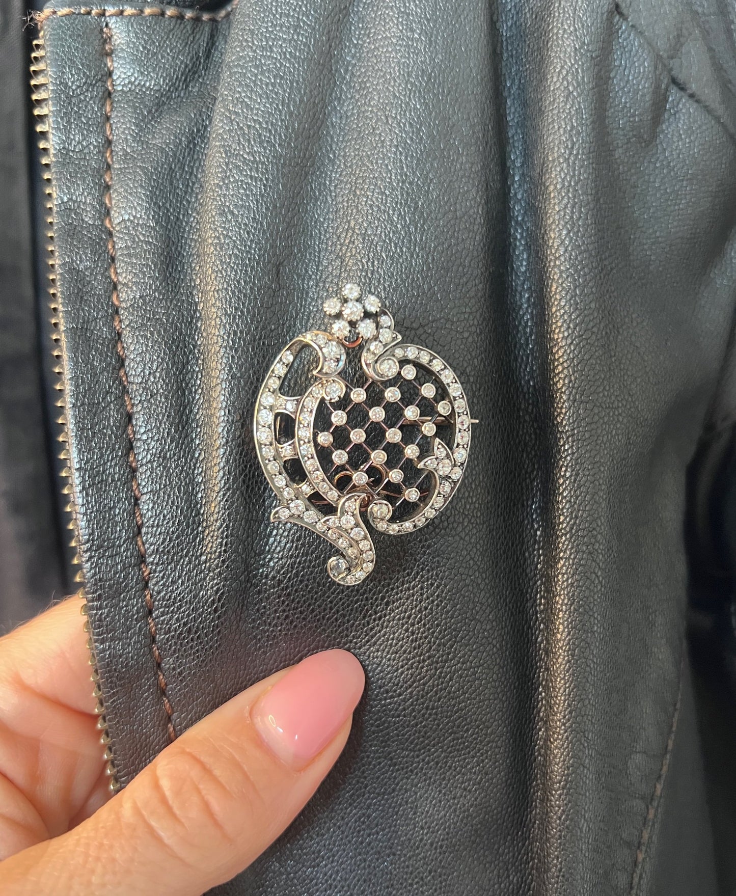 An openwork diamond set antique brooch in yellow gold and silver, modelled on a black leather jacket