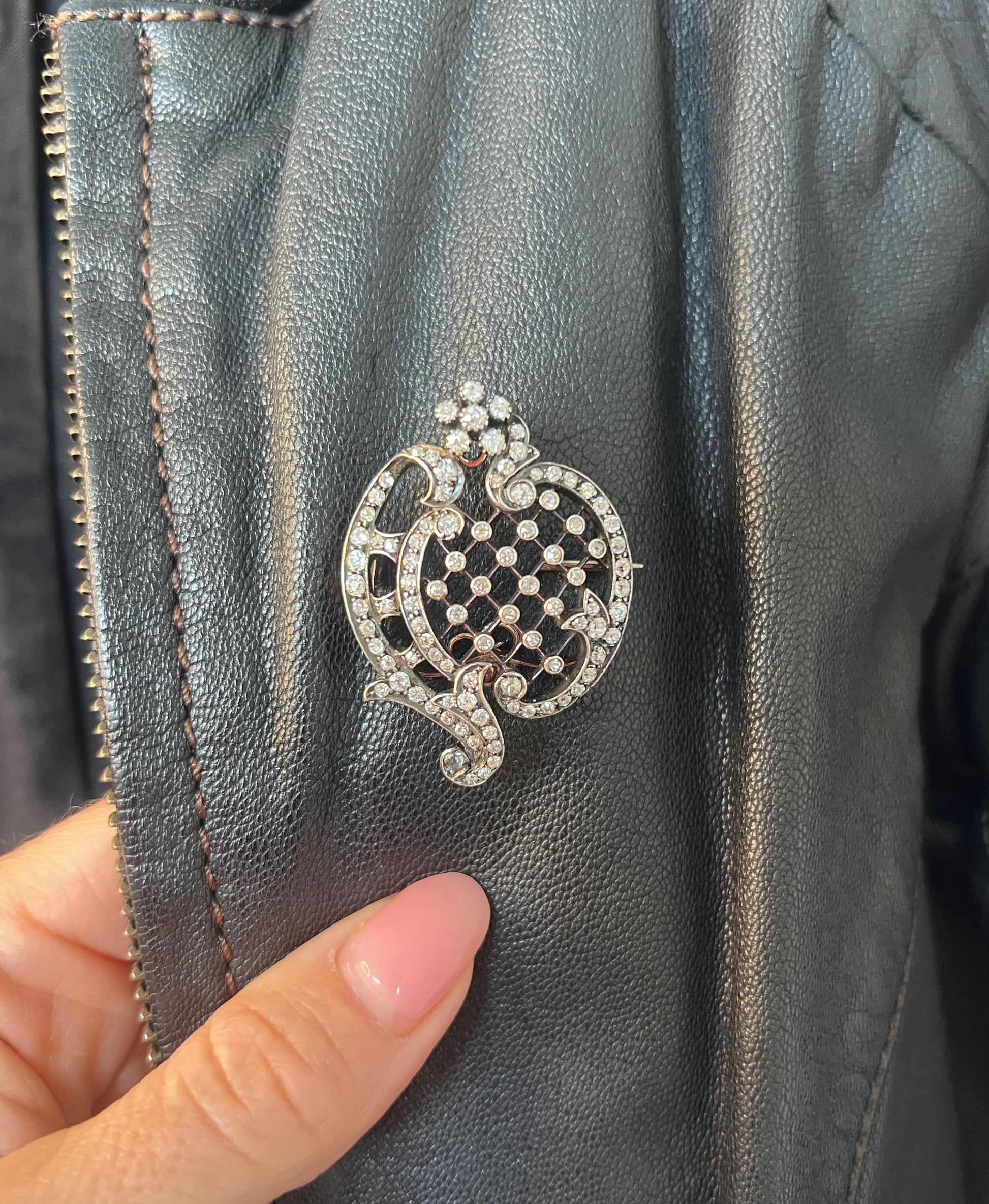 An openwork diamond set antique brooch in yellow gold and silver, modelled on a black leather jacket