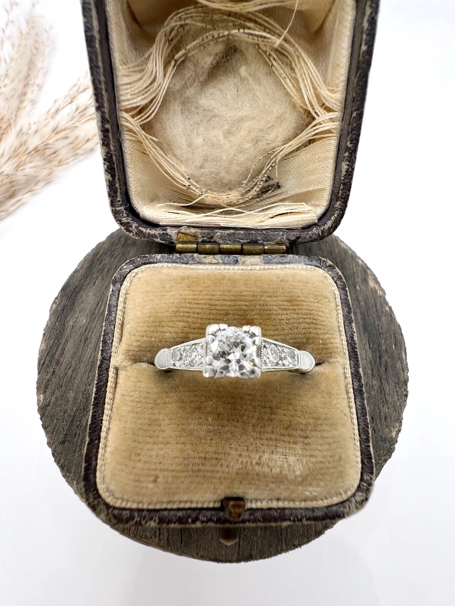 A solitaire diamond ring in platinum, with diamond set shoulders, in a ring box