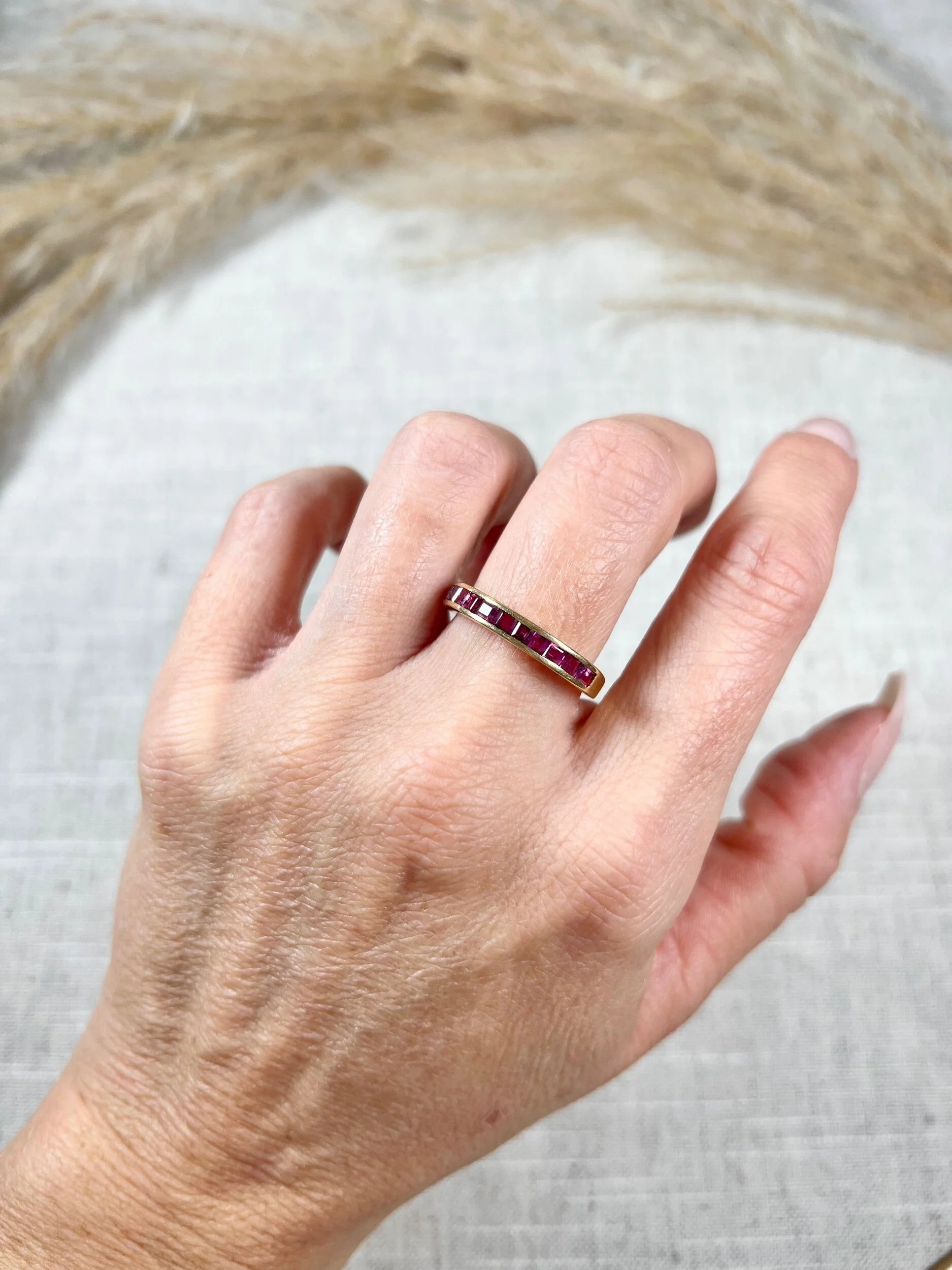 A yellow gold ruby channel set eternity band, modelled on a hand