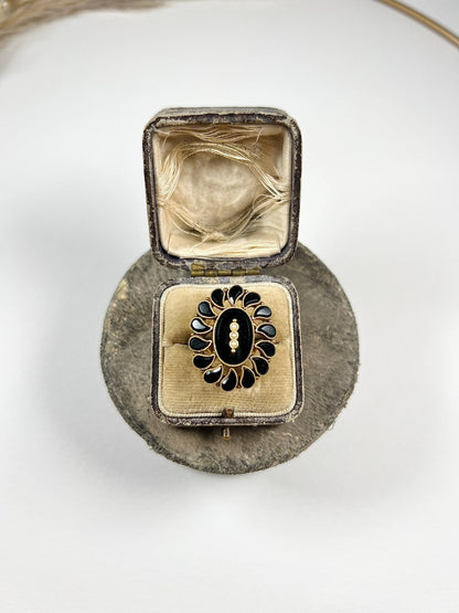 A black onyx and seed pearl fancy halo cluster ring in yellow gold, in a ring box