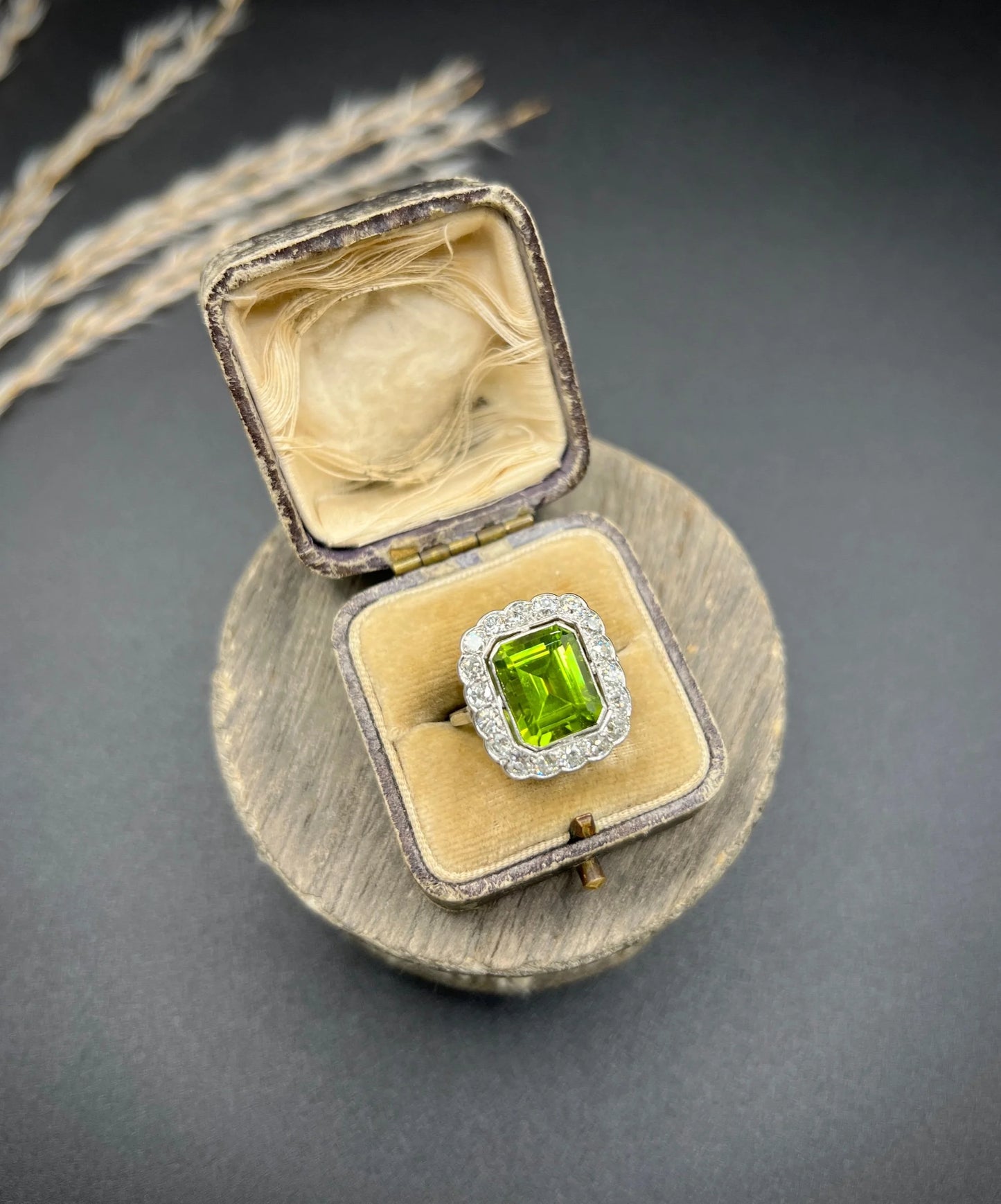 A cushion shaped peridot and diamond cluster ring in white metal, in an antique ring box