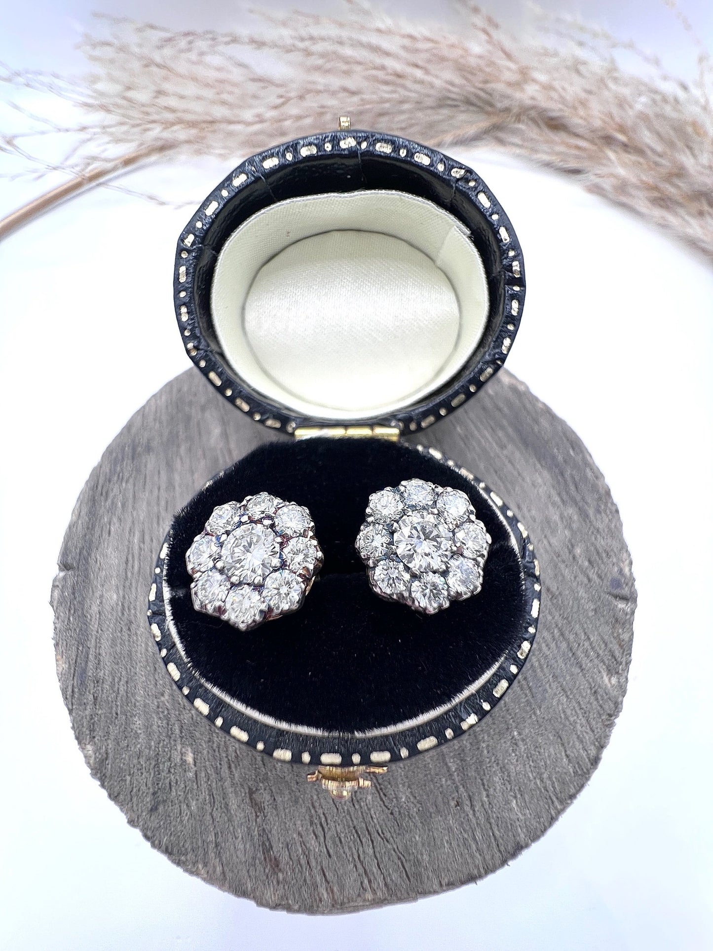 A pair of diamond daisy cluster stud earrings in yellow and white gold, in an earring box