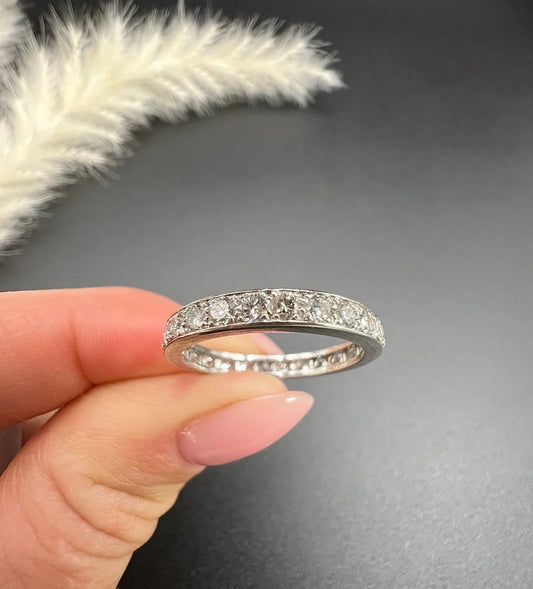 A diamond full eternity band ring in platinum, held in a hand