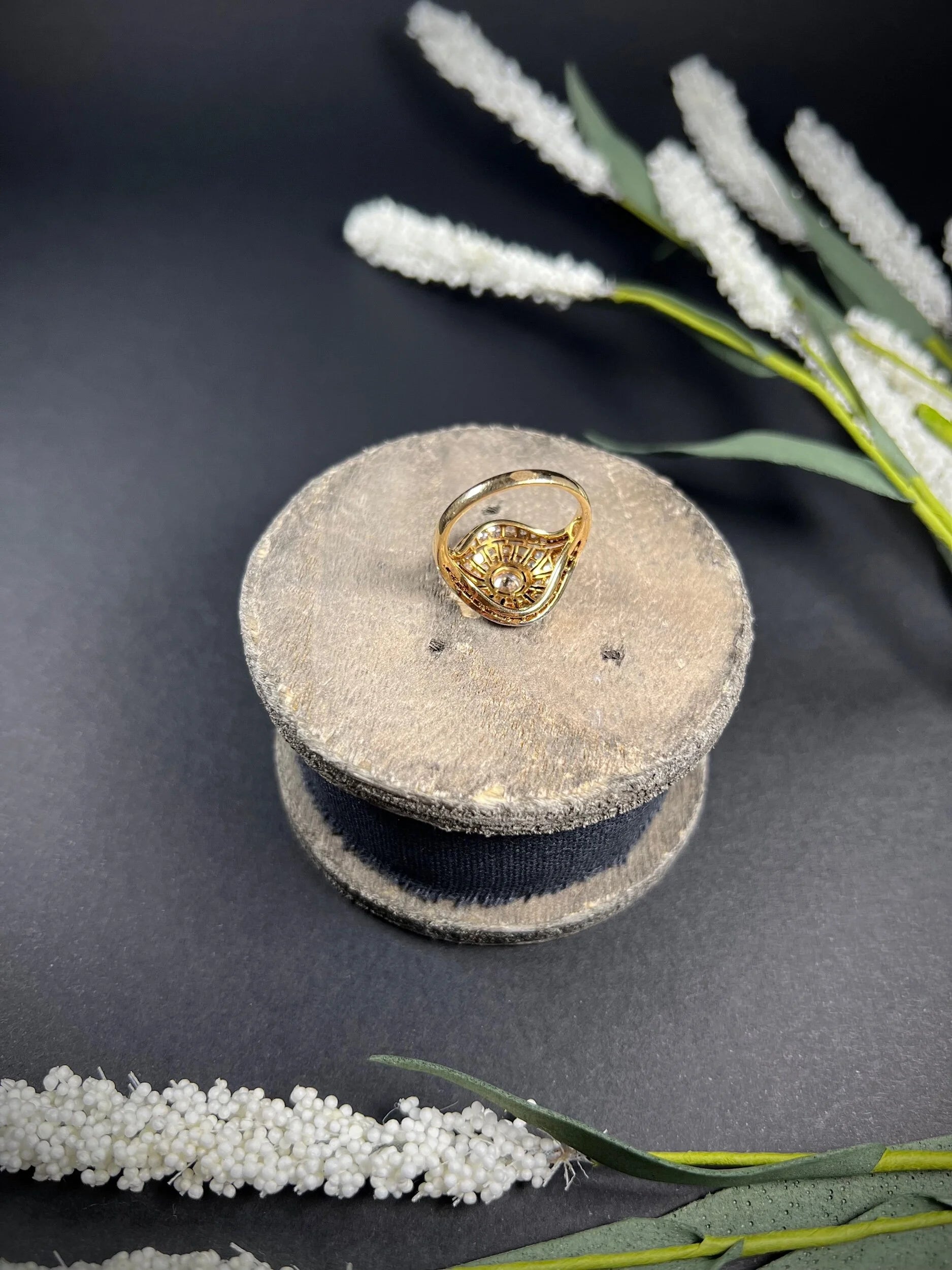 A diamond cocktail ring in yellow and white metal sat on top of a wooden object