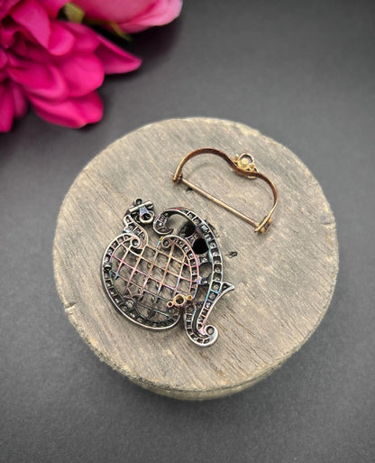 An openwork diamond set antique brooch in yellow gold and silver, showing the detachable fitting