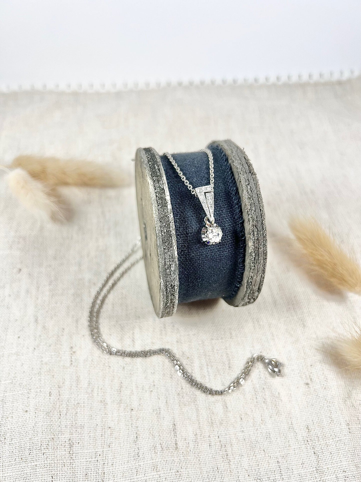 An old cut diamond pendant in white metal with a matching chain, on a circular object