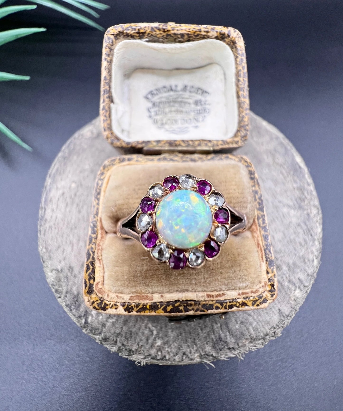 A daisy style cluster ring in rose gold with opal, ruby and diamond, in an antique ring box
