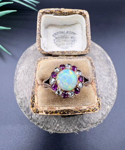 A daisy style cluster ring in rose gold with opal, ruby and diamond, in an antique ring box