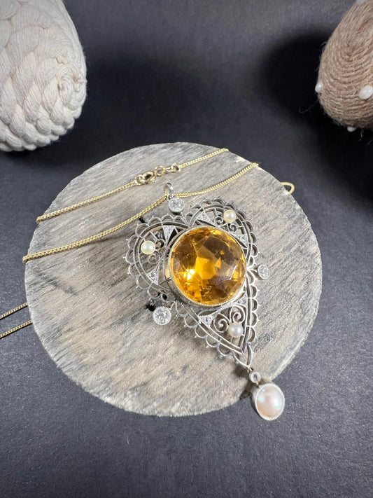 A citrine, diamond and pearl decorative pendant, on a yellow gold chain, on a wooden spool