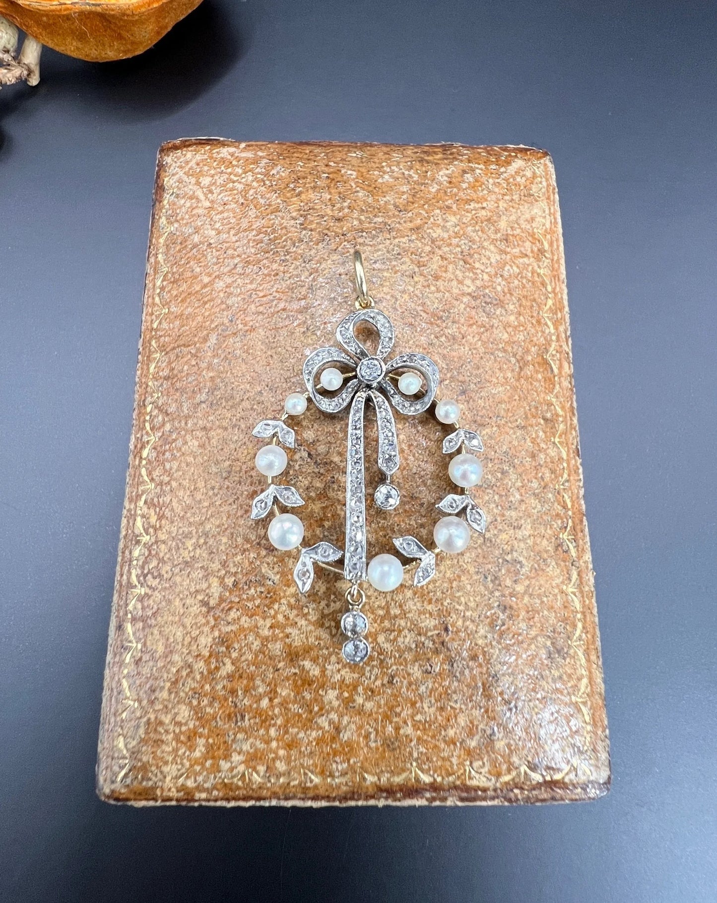 A pearl and diamond bow pendant in gold and platinum