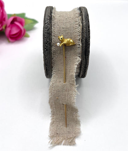 A yellow gold cat playing with a pearl ball stick pin