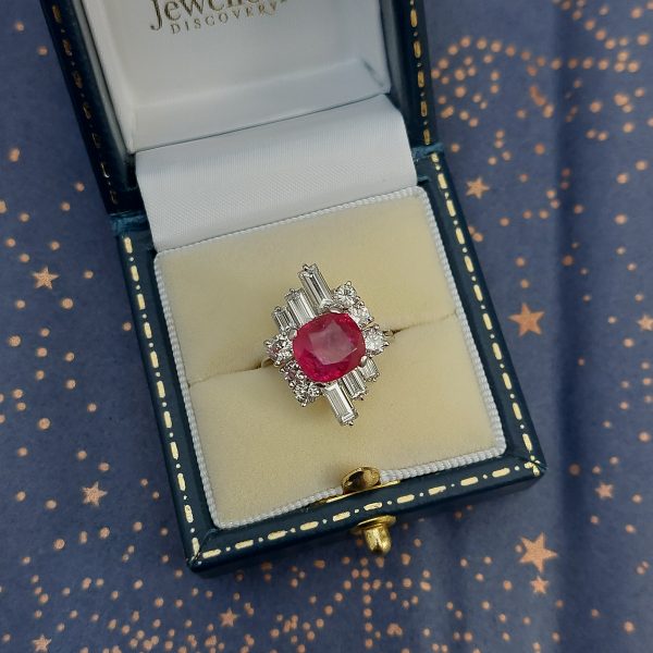 A vintage ruby and diamond cluster ring with cushion cut certified Burmese ruby surrounded by baguette- and diamond -cut ballerina cluster.