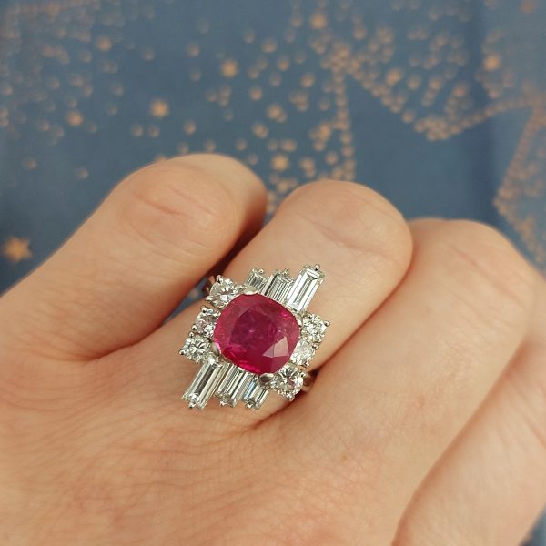 A vintage ruby and diamond cluster ring with cushion cut certified Burmese ruby surrounded by baguette- and diamond -cut ballerina cluster.