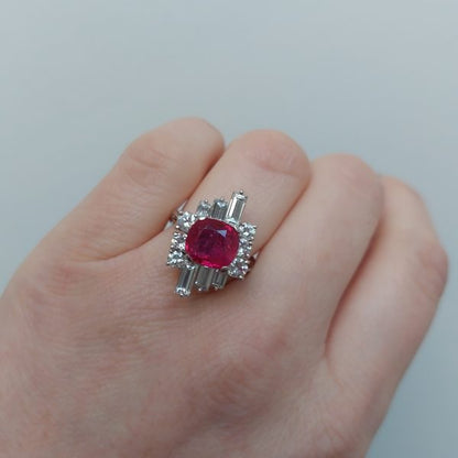 A vintage ruby and diamond cluster ring with cushion cut certified Burmese ruby surrounded by baguette- and diamond -cut ballerina cluster.