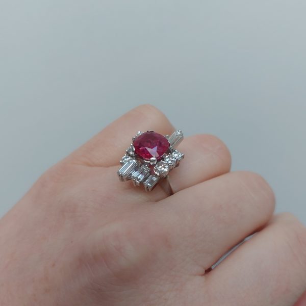 A vintage ruby and diamond cluster ring with cushion cut certified Burmese ruby surrounded by baguette- and diamond -cut ballerina cluster.