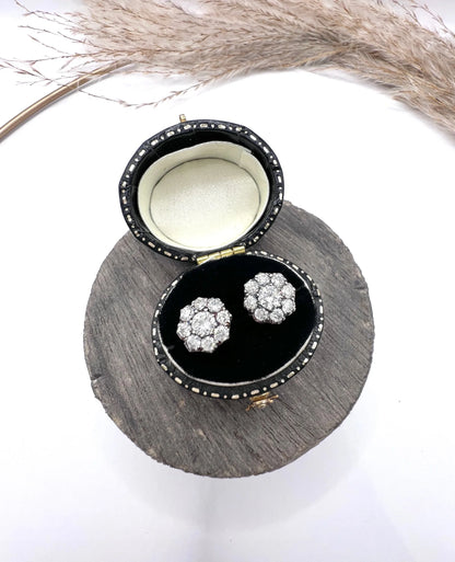 A pair of diamond daisy cluster stud earrings in yellow and white gold, in an earring box