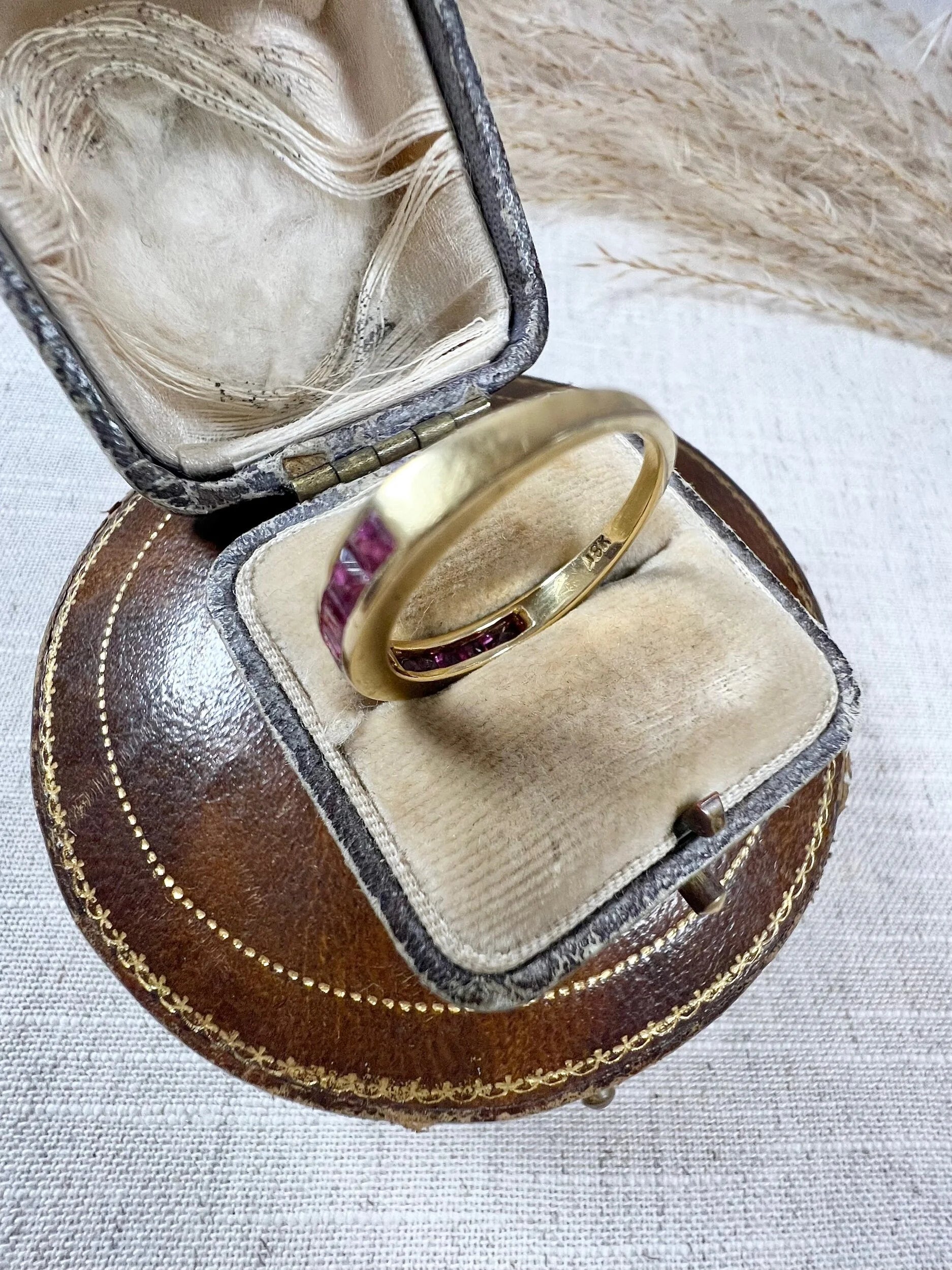 A yellow gold ruby channel set eternity band, in an antique ring box