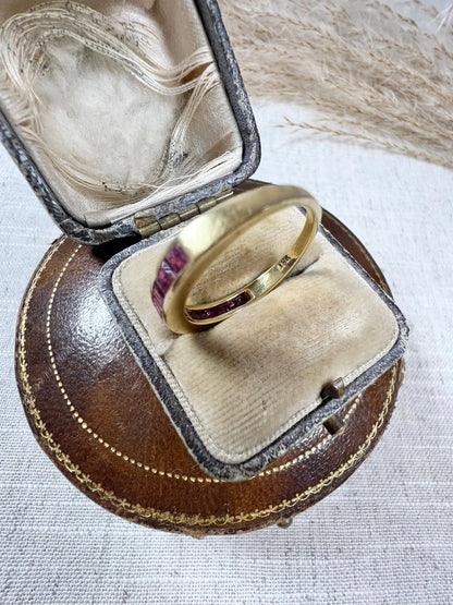 A yellow gold ruby channel set eternity band, in an antique ring box