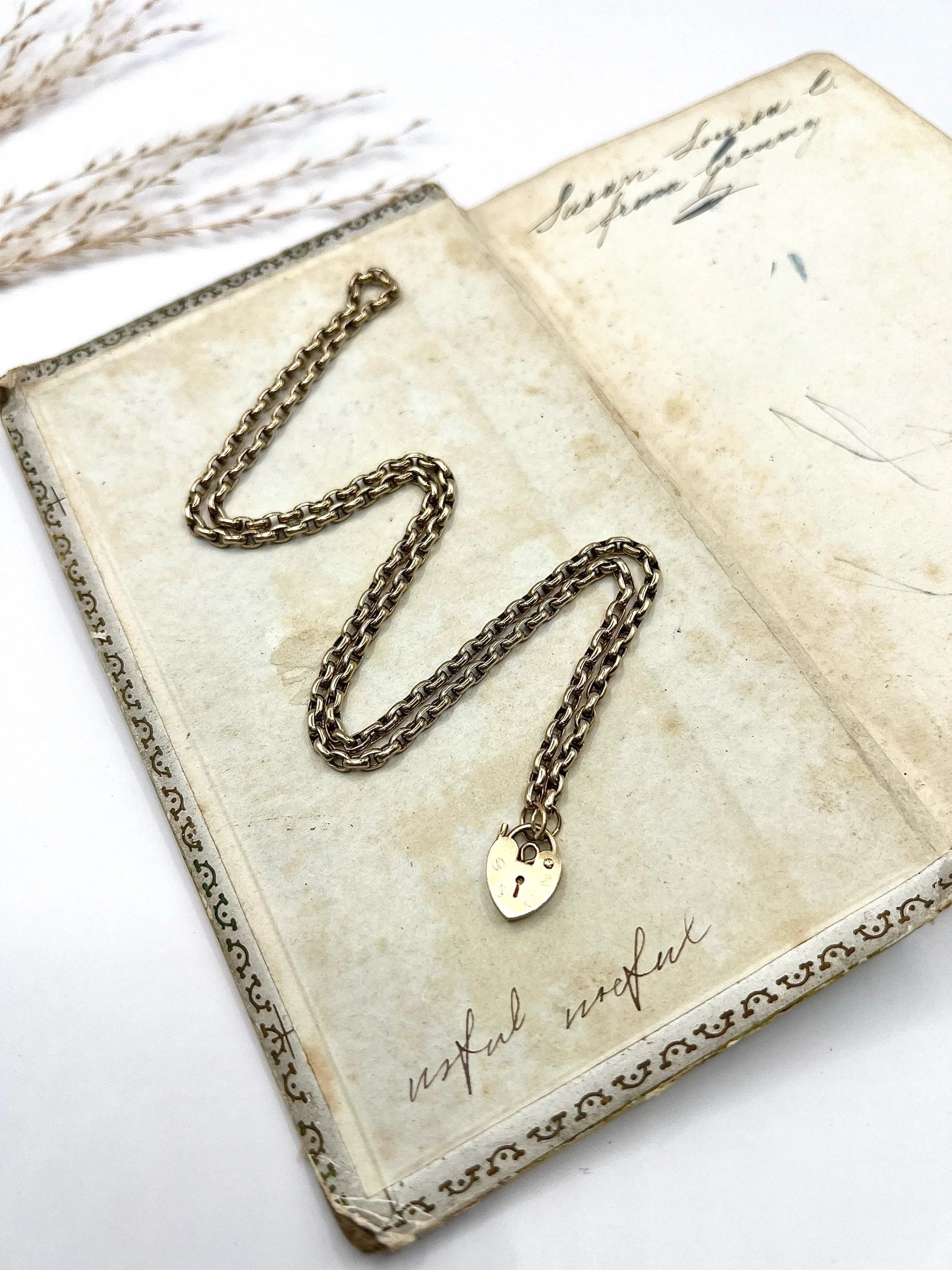 A gold belcher link chain with a heart shaped padlock clasp pendant