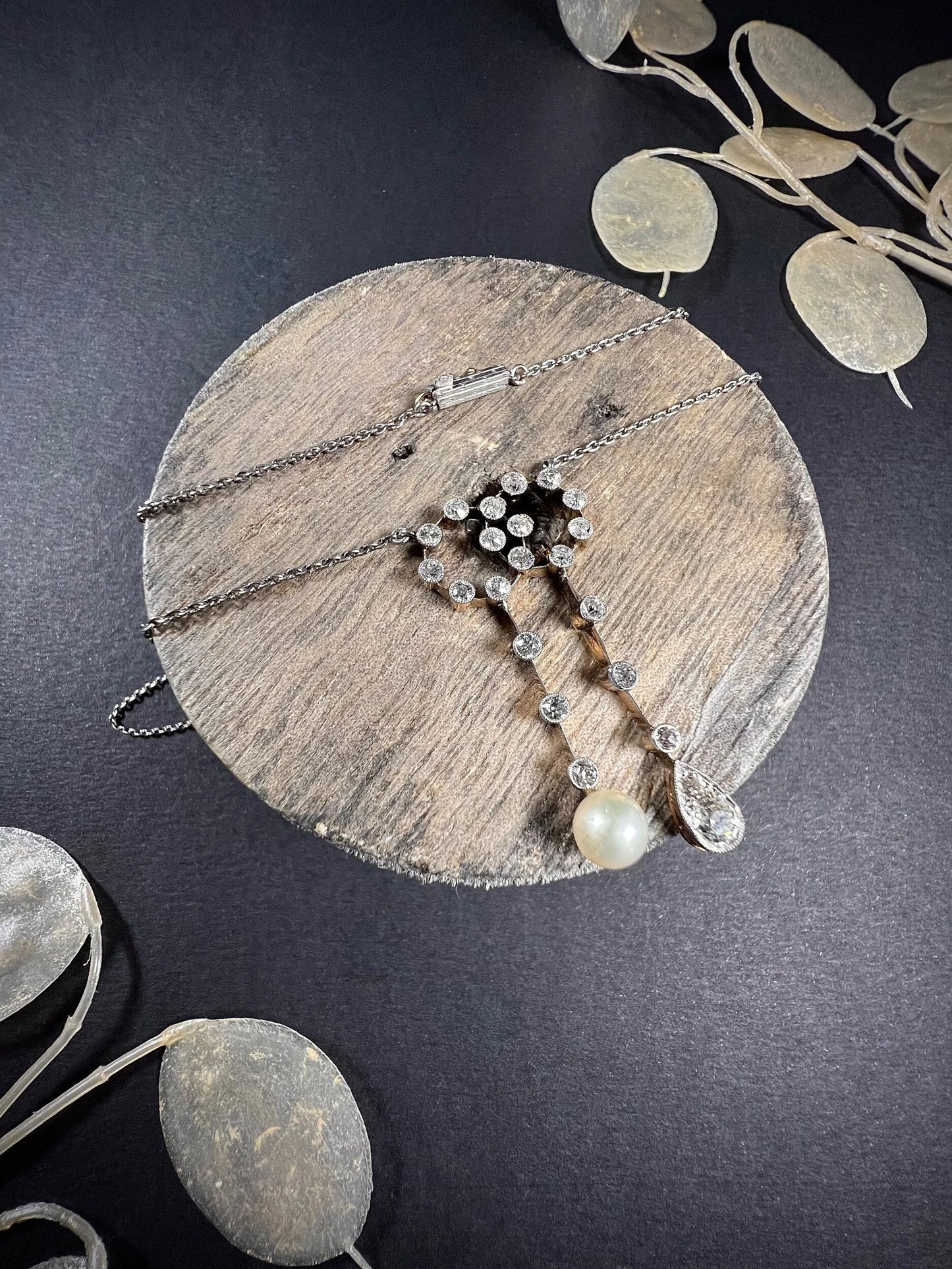 An antique diamond and pearl double drop pendant necklace, on a wooden spool