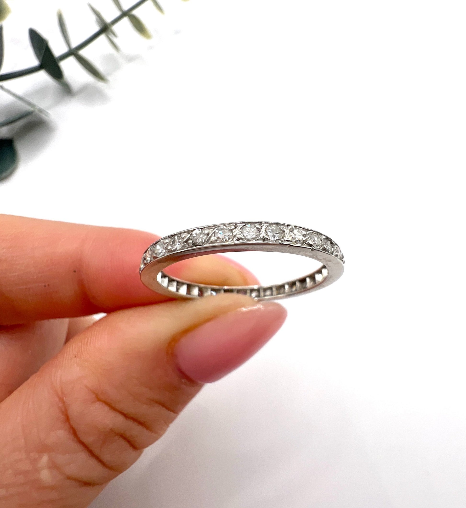 A platinum and diamond full eternity band ring, held in a hand