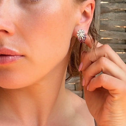 A diamond and ruby fancy cluster stud earring in platinum, modelled in an ear