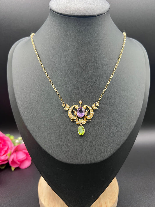 A yellow gold peridot, amethyst and seed pearl pendant necklace, on a black jewellery bust