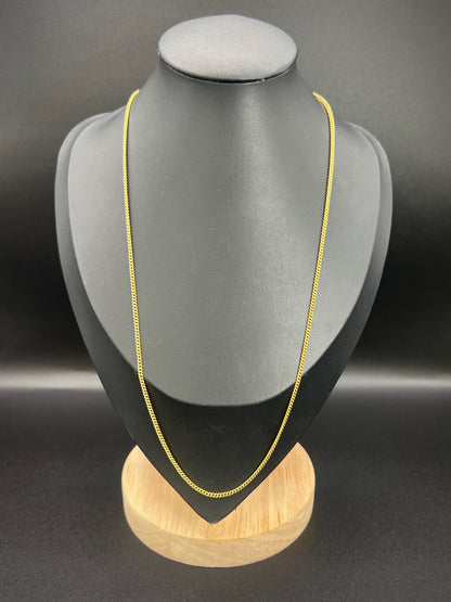 A yellow gold chain necklace, on a black jewellery bust