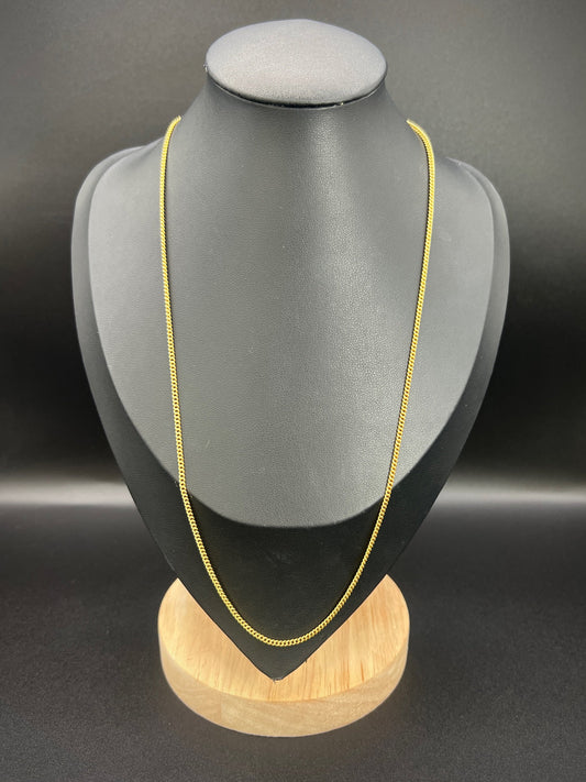 A yellow gold chain necklace, on a black jewellery bust